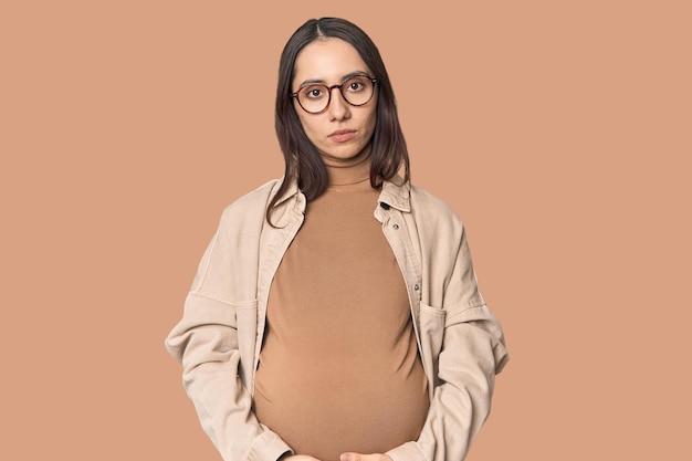 Mulher jovem caucasiana grávida mostrando a maternidade no fundo do estúdio
