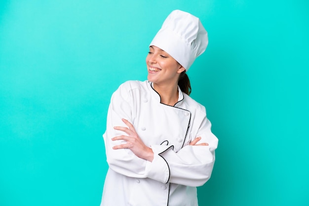 Mulher jovem chef caucasiana isolada em fundo azul, feliz e sorridente