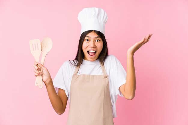 Mulher jovem chef chinês recebendo uma agradável surpresa, animado e levantando as mãos.