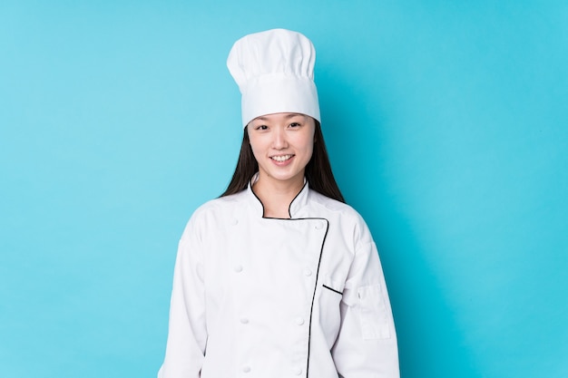 Mulher jovem chef chinesa isolada feliz, sorridente e alegre.