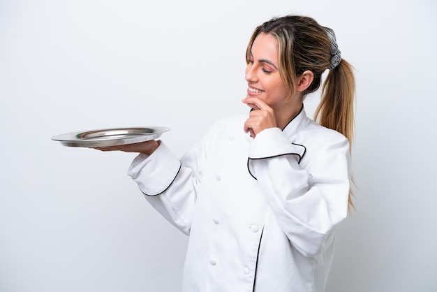 Mulher jovem chef com bandeja isolada no fundo branco, olhando para o lado e sorrindo