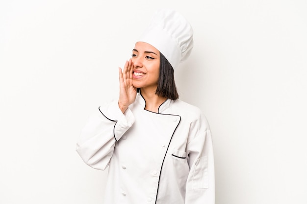 Mulher jovem chef hispânico isolada no fundo branco gritando e segurando a palma da mão perto da boca aberta