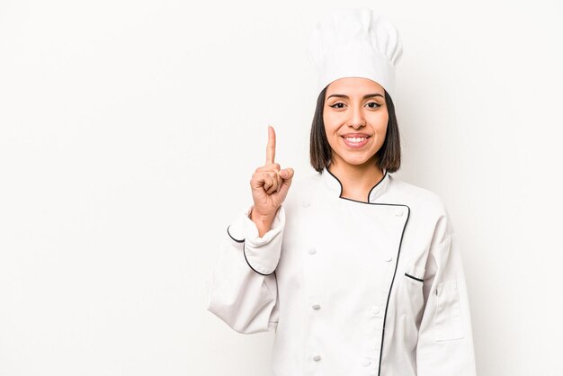 Mulher jovem chef hispânico isolada no fundo branco, mostrando o número um com o dedo