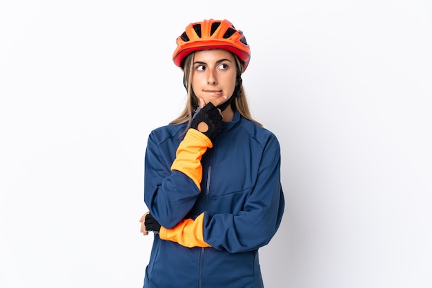 Mulher jovem ciclista hispânica isolada na parede branca tendo dúvidas e pensando
