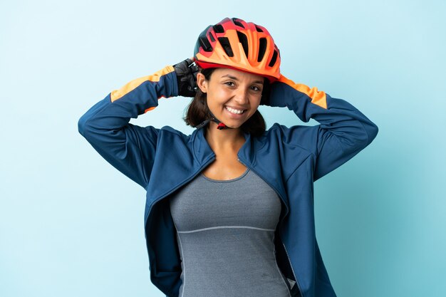 Mulher jovem ciclista isolada em um fundo azul rindo