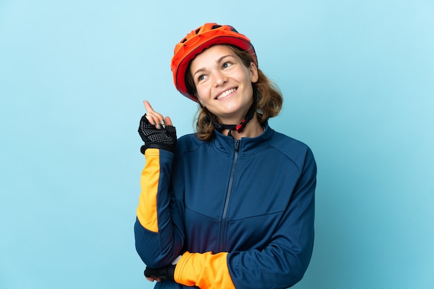 Mulher jovem ciclista isolada na parede azul apontando uma ótima ideia