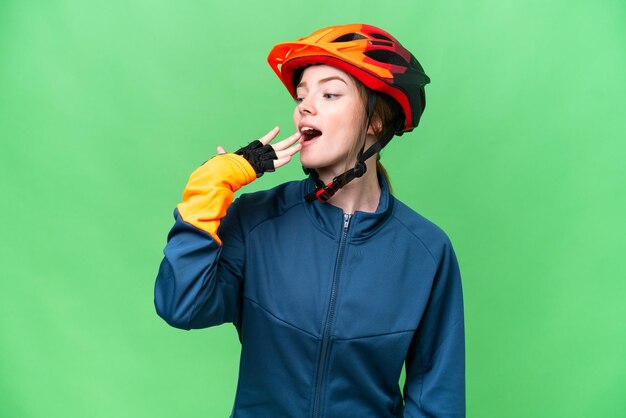 Mulher jovem ciclista sobre fundo croma chave isolado bocejando e cobrindo a boca aberta com a mão