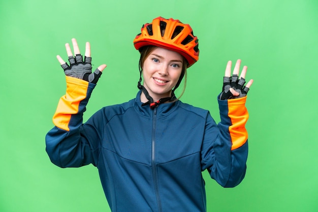 Mulher jovem ciclista sobre fundo croma chave isolado contando nove com os dedos