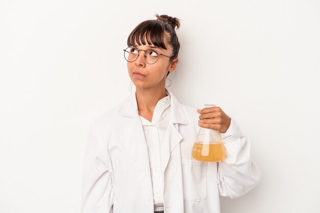 Mulher jovem cientista mestiça segurando um tubo de ensaio isolado no fundo branco e sonhando em alcançar objetivos e propósitos