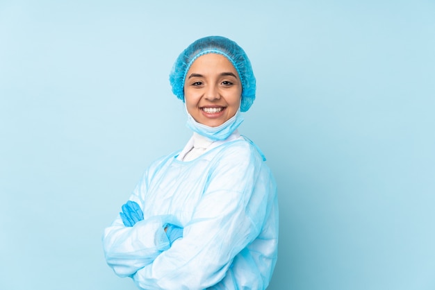 Mulher jovem cirurgião de uniforme azul com os braços cruzados e olhando para a frente