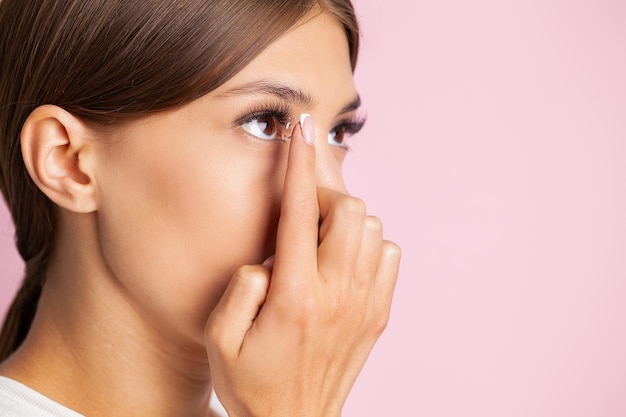 Mulher jovem colocando lentes de contato no olho de perto