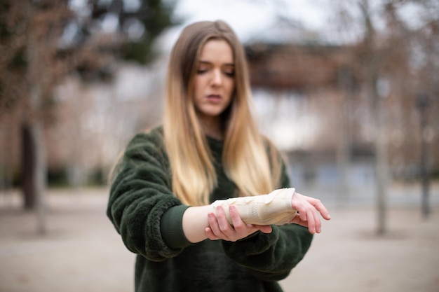 Mulher jovem com a mão fraturada de pé na rua