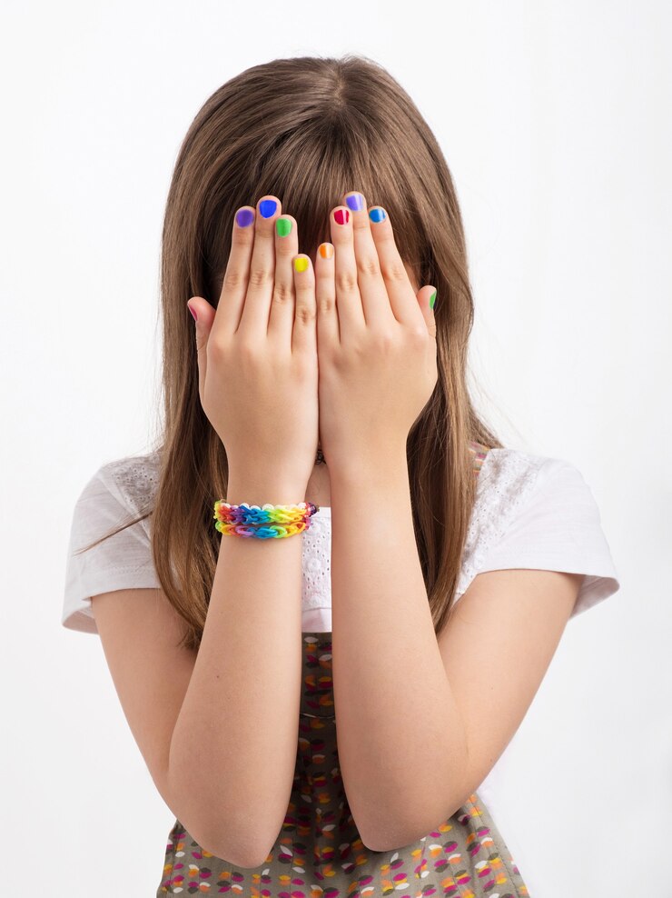 Foto mulher jovem com as mãos cobrindo o rosto, as unhas e a pulseira lgbt. conceito de vergonha ou medo
