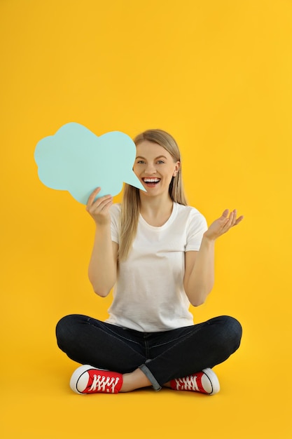 Mulher jovem com balão em fundo amarelo