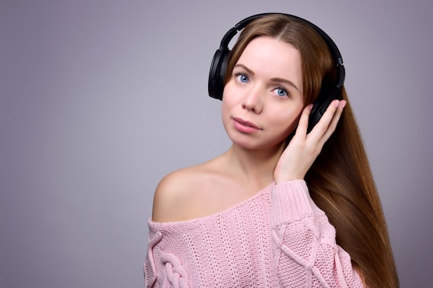 Mulher jovem com cabelo comprido em grandes fones de ouvido sem fio