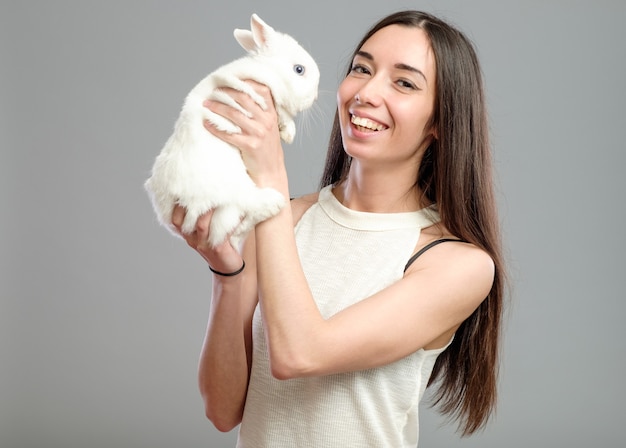 Mulher jovem com cabelo comprido segurando um coelho