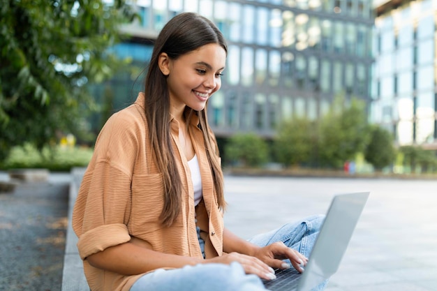 Mulher jovem com cabelo comprido usando notebook no parque