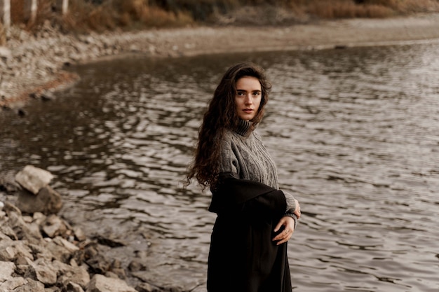 Mulher jovem com cabelo encaracolado em pé junto ao lago