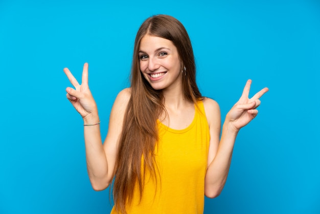 Mulher jovem, com, cabelo longo, sobre, isolado, parede azul, mostrando, sinal vitória, com, ambos, mãos