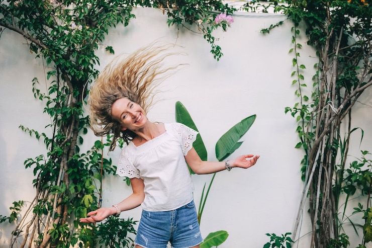 Foto mulher jovem com cabelos fluentes desfrutando de um dia ensolarado em um jardim exuberante com plantas verdes