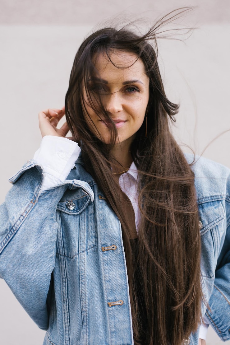 Foto mulher jovem com cabelos longos está vestindo uma jaqueta de jeans azul e sorrindo