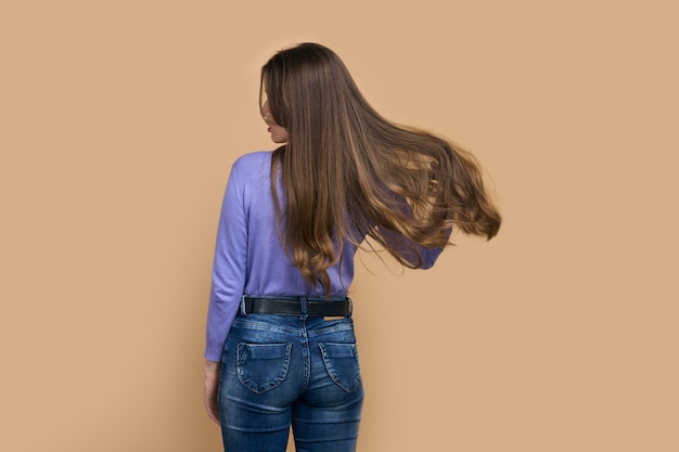 Foto mulher jovem com cabelos longos soltos isolados em fundo bege penteado cuidados com o cabelo