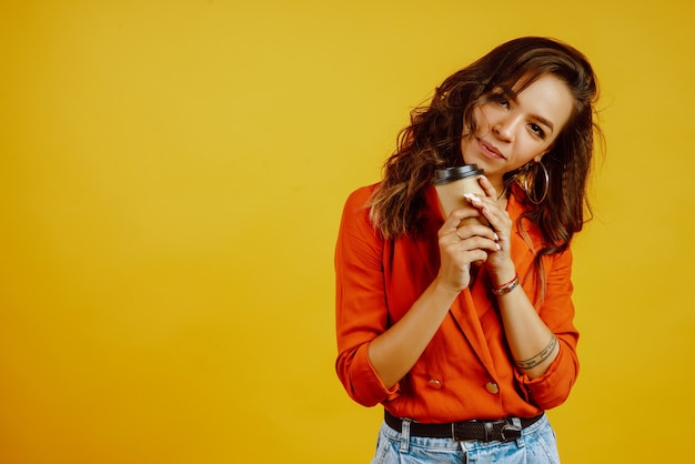 Mulher jovem com café posando em amarelo