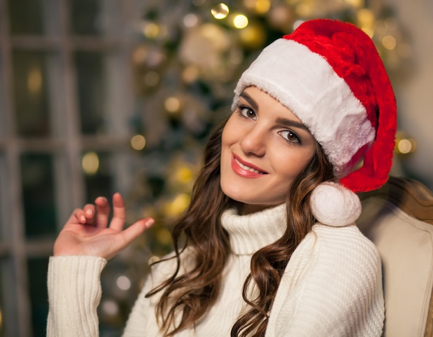 Mulher jovem com caixa de presente perto da árvore de natal