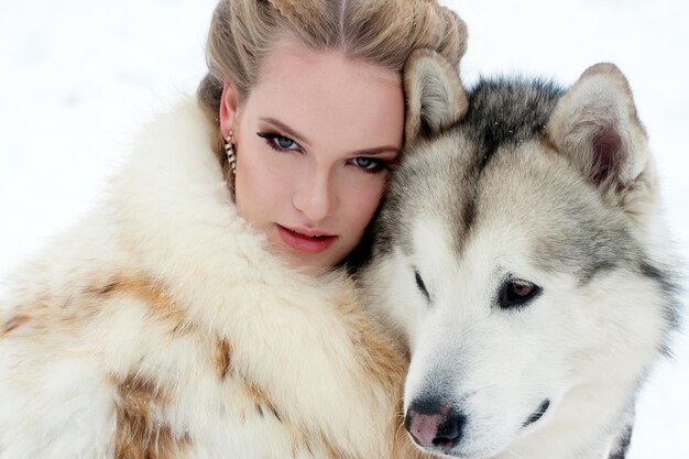 Foto mulher jovem com cão lobo na neve