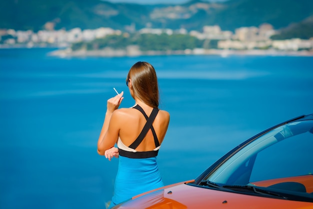 Mulher jovem com carro à beira-mar