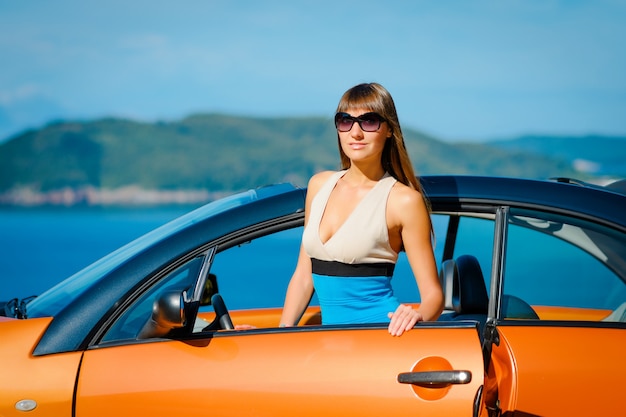 Mulher jovem com carro à beira-mar