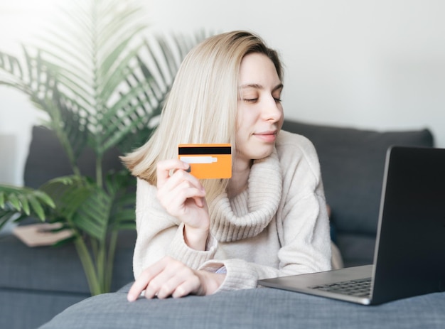 Mulher jovem com cartão de crédito e usando computador portátil