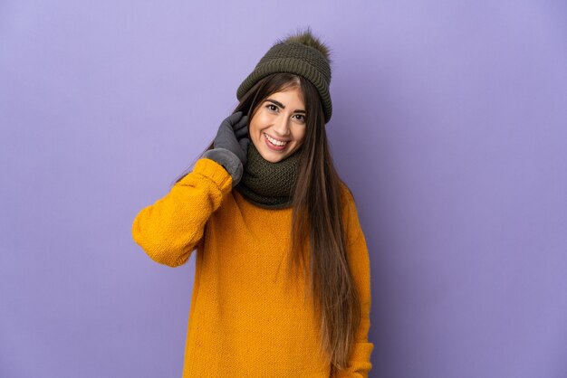 Mulher jovem com chapéu de inverno isolada na parede roxa rindo