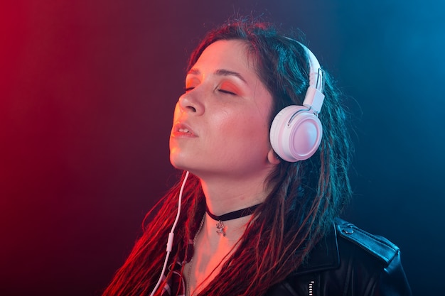 Mulher jovem com dreadlocks curtindo a música em seus fones de ouvido