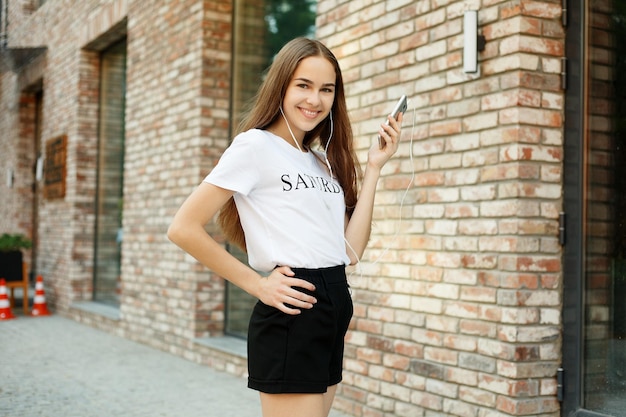 Foto mulher jovem com fones de ouvido pendurados no telemóvel