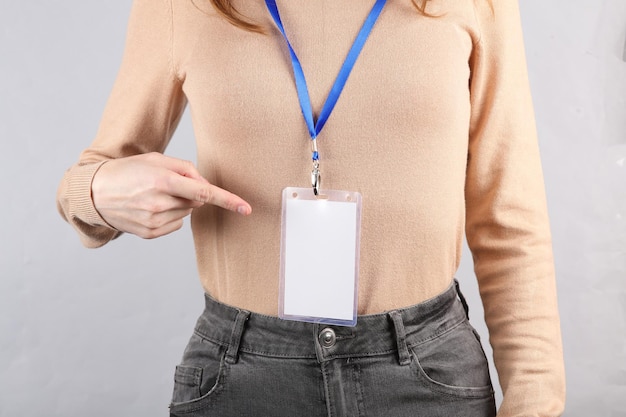 Mulher jovem com identificação cartão de identificação branco em branco em fundo cinza