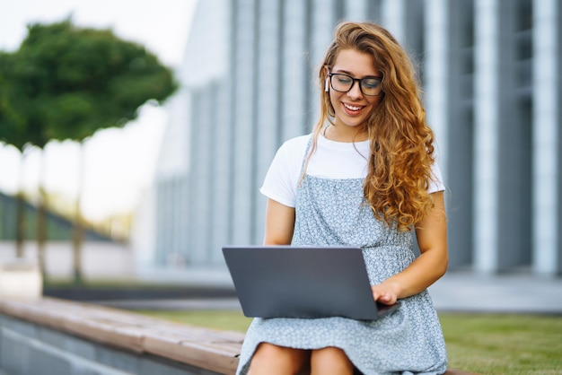 Mulher jovem com laptop ao ar livre Educação on-line Freelancer Negócios compras blogging