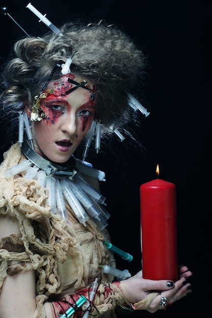Mulher jovem com maquiagem brilhante usando fantasia de carnaval segurando uma vela