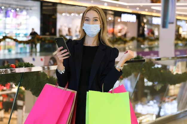 Mulher jovem com máscara protetora e sacolas de compras