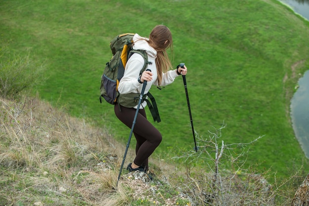 Mulher jovem com mochila caminhando nas montanhas conceito de caminhada penhascos de caminhada viajante de viagem