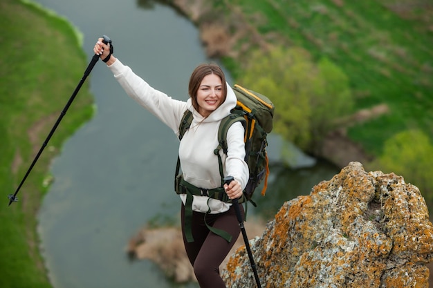 Mulher jovem com mochila caminhando nas montanhas conceito de caminhada penhascos de caminhada viajante de viagem