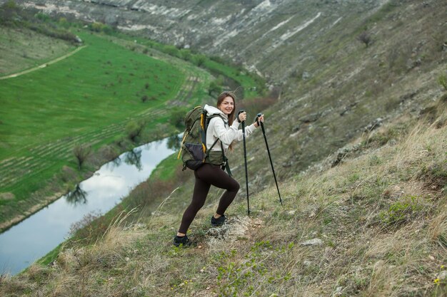 Mulher jovem com mochila caminhando nas montanhas conceito de caminhada penhascos de caminhada viajante de viagem