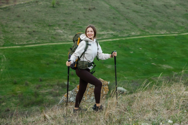 Mulher jovem com mochila caminhando nas montanhas conceito de caminhada penhascos de caminhada viajante de viagem