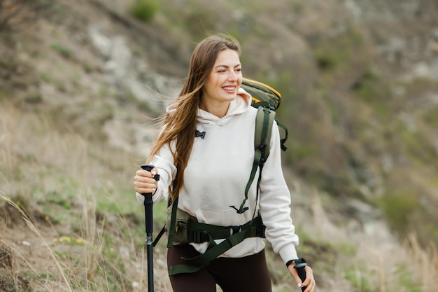 Mulher jovem com mochila caminhando nas montanhas conceito de caminhada penhascos de caminhada viajante de viagem