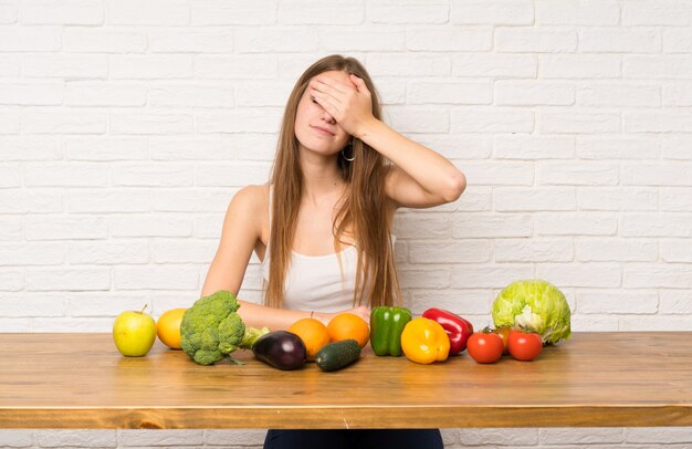 Mulher jovem, com, muitos, legumes, cobertura, olhos, por, mãos