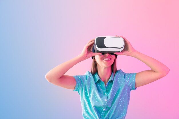 Mulher jovem com óculos de realidade virtual na cor de fundo