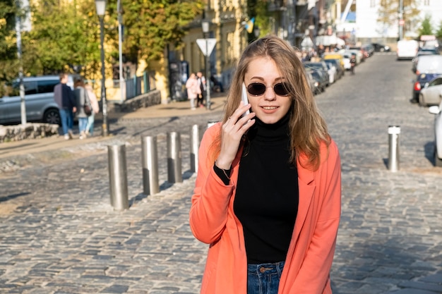 Mulher jovem com óculos de sol falando no celular