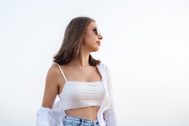 Mulher jovem com óculos de sol olhando para o horizonte, horizontal, copie o espaço