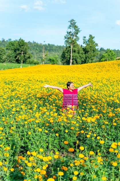 Foto mulher jovem com os braços estendidos de pé no campo de margarida