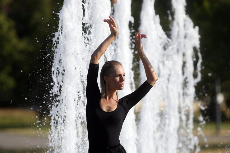 Foto mulher jovem com os braços levantados na cachoeira